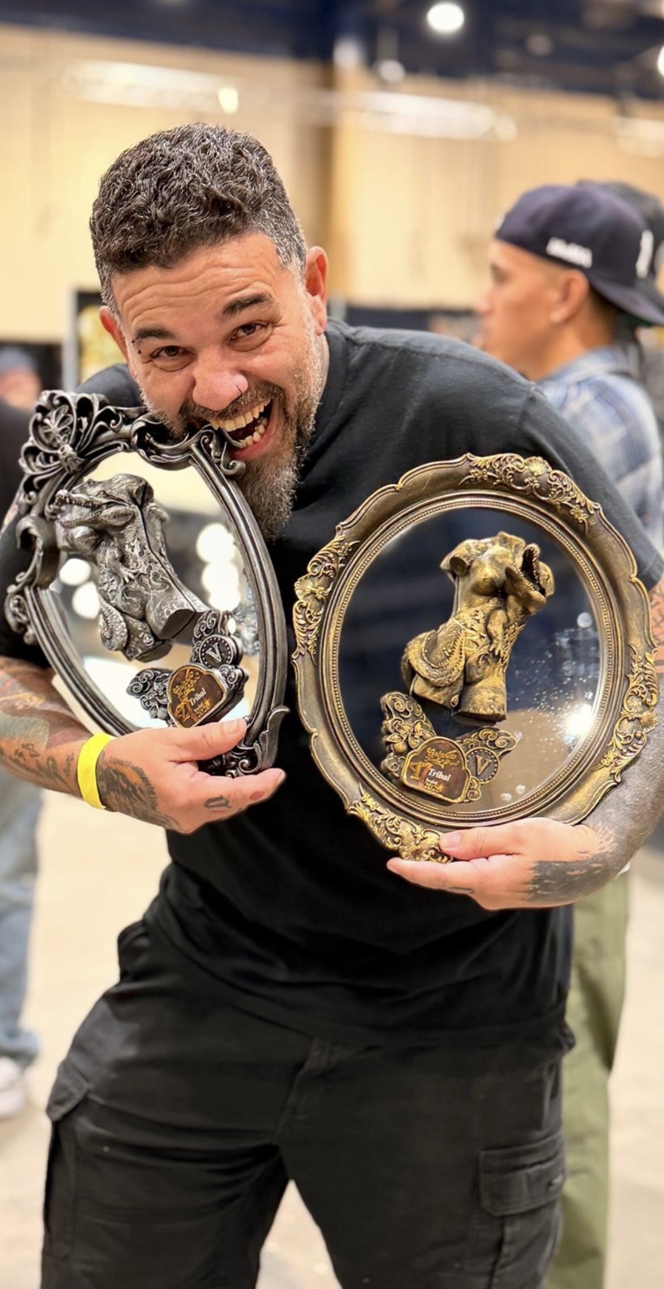 Tattoo artist Tchelo holding two awards